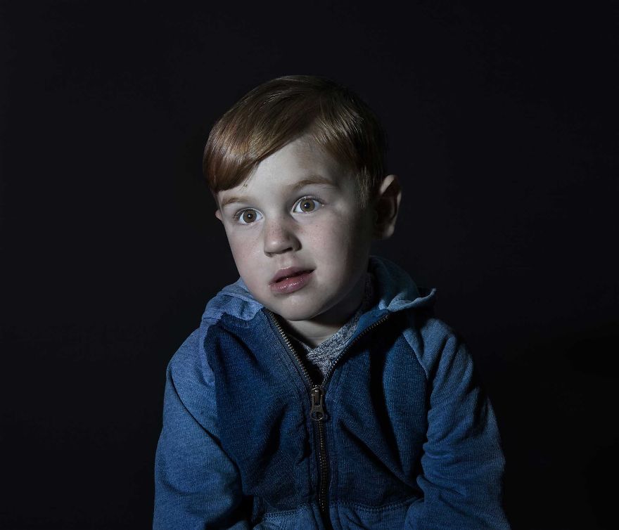 Portrait of a red head boy in blue sweater vacantly staring. He is engrossed in TV.